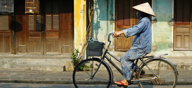 A Vietnamese lady cycling along the streets of Hoi An